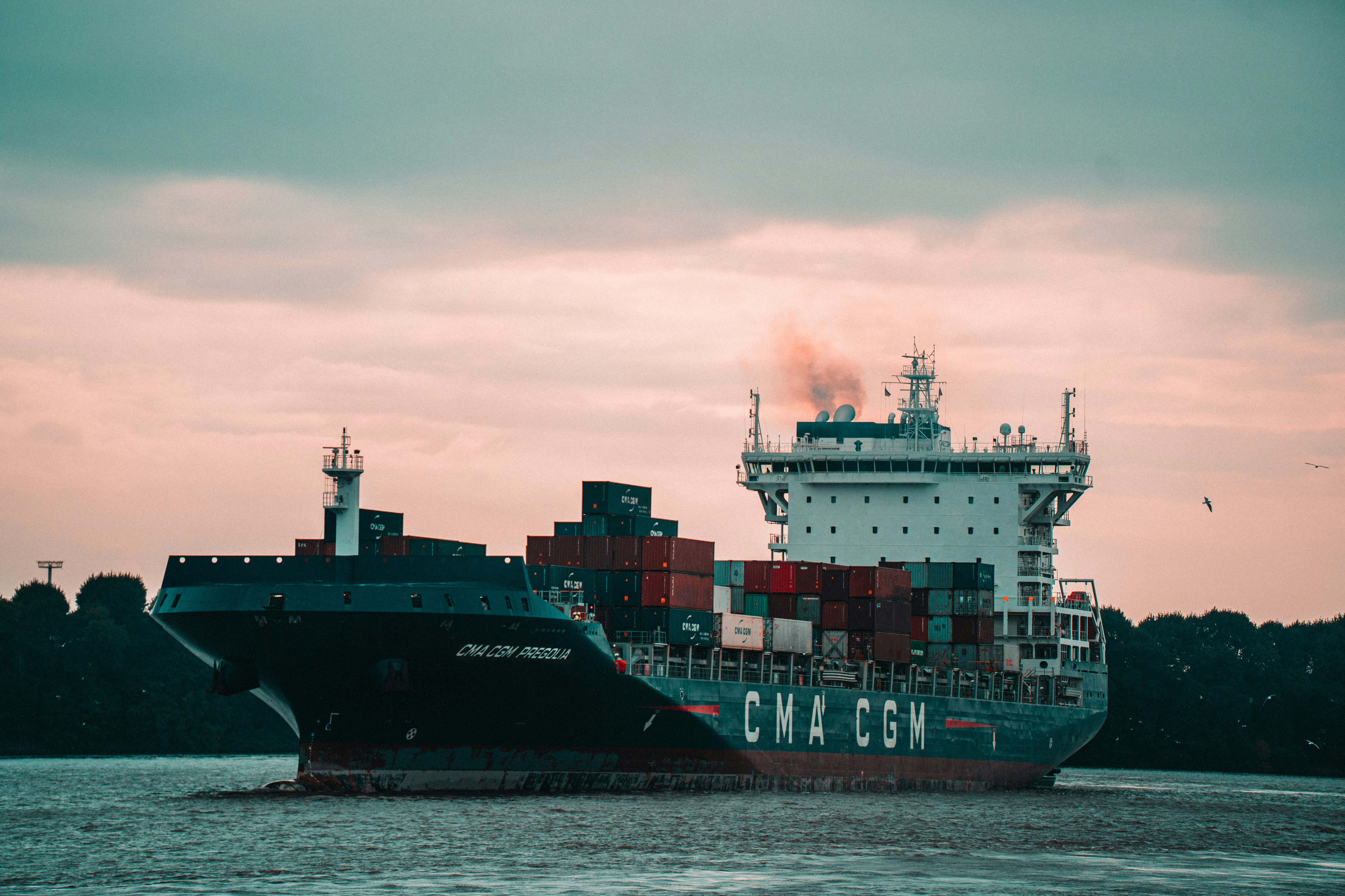 Container ship at sea under a pink sunset sky