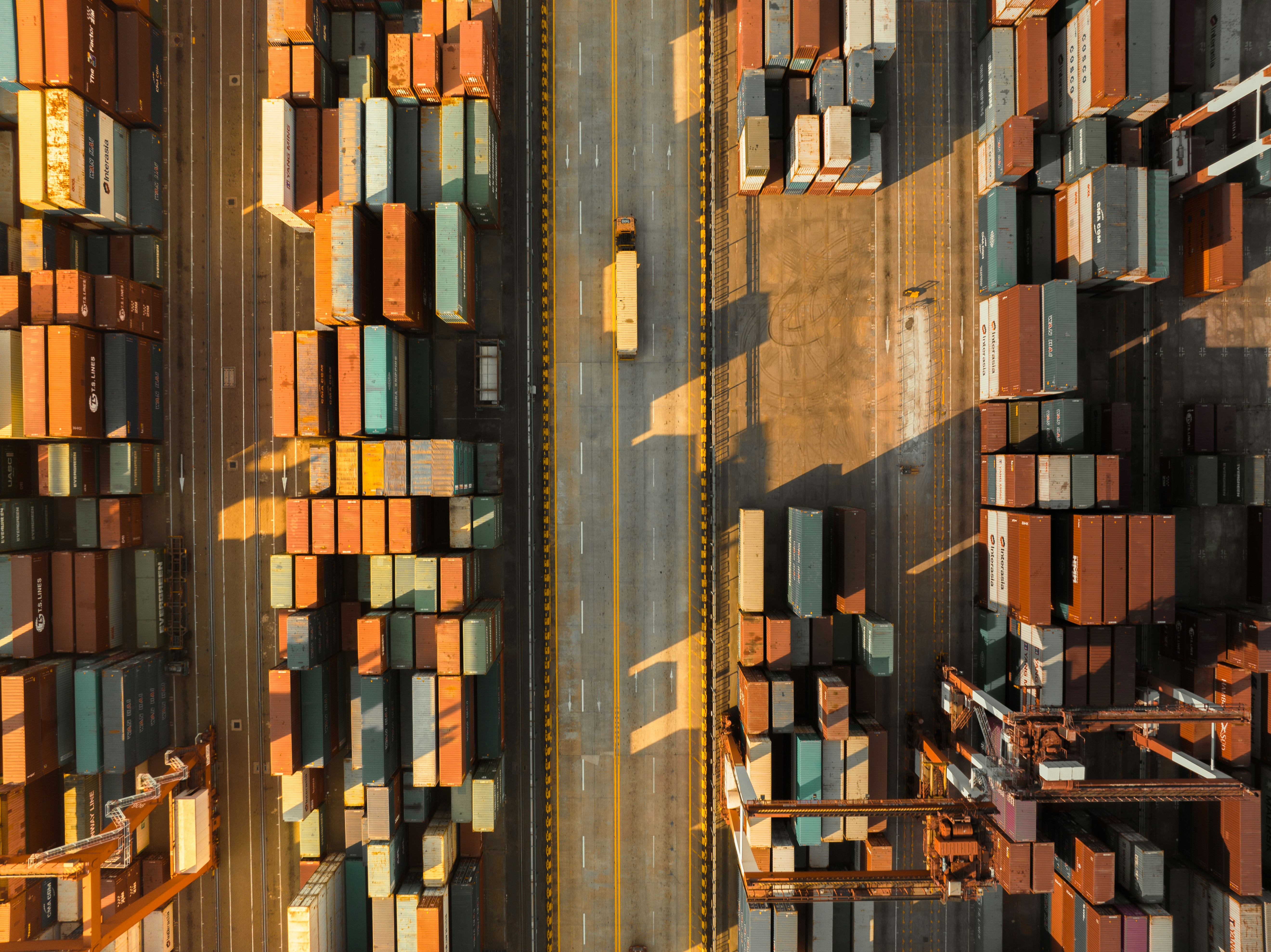 Rows of shipping containers and a crane in warm evening light