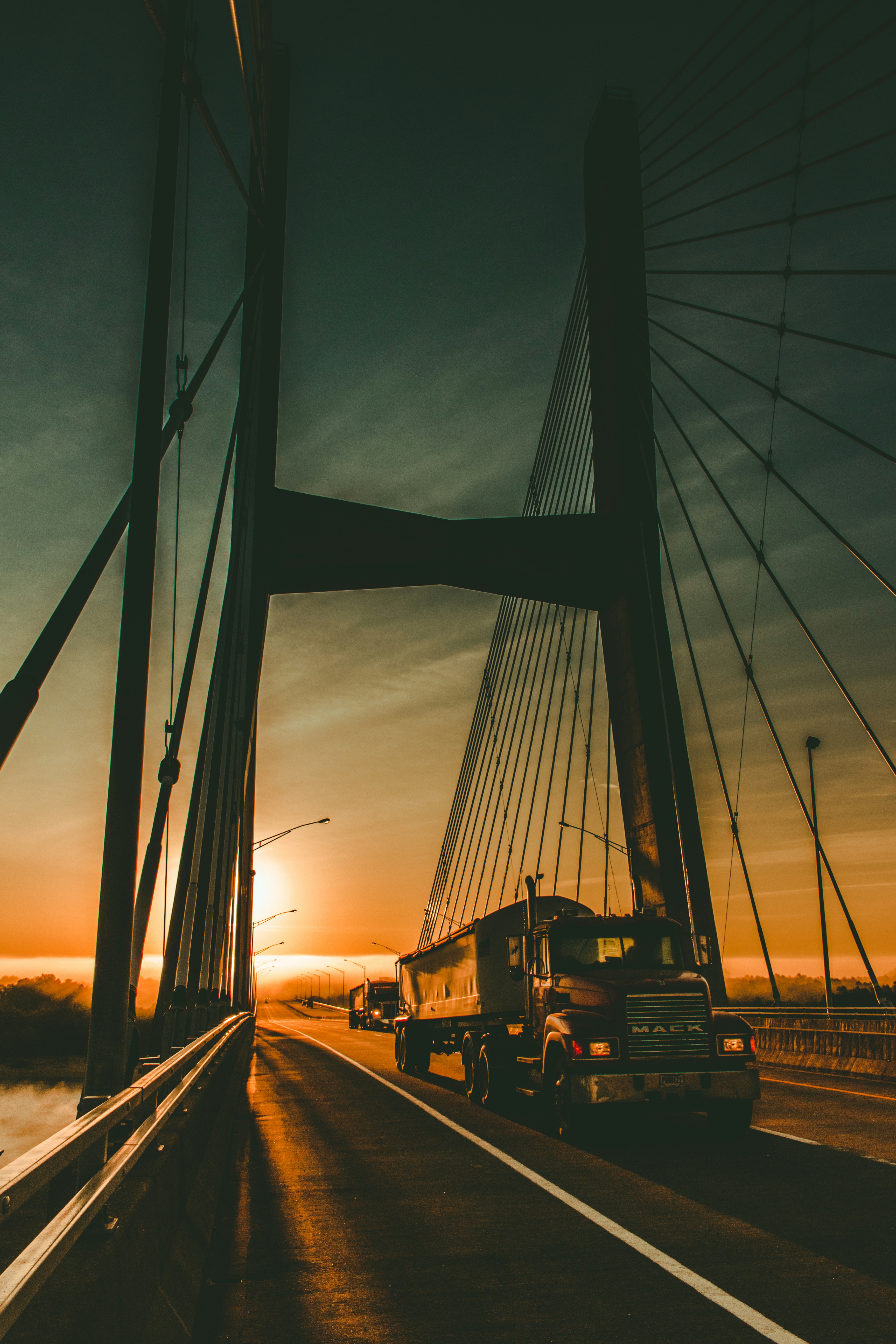 A truck crossing a cable-stayed bridge at sunset