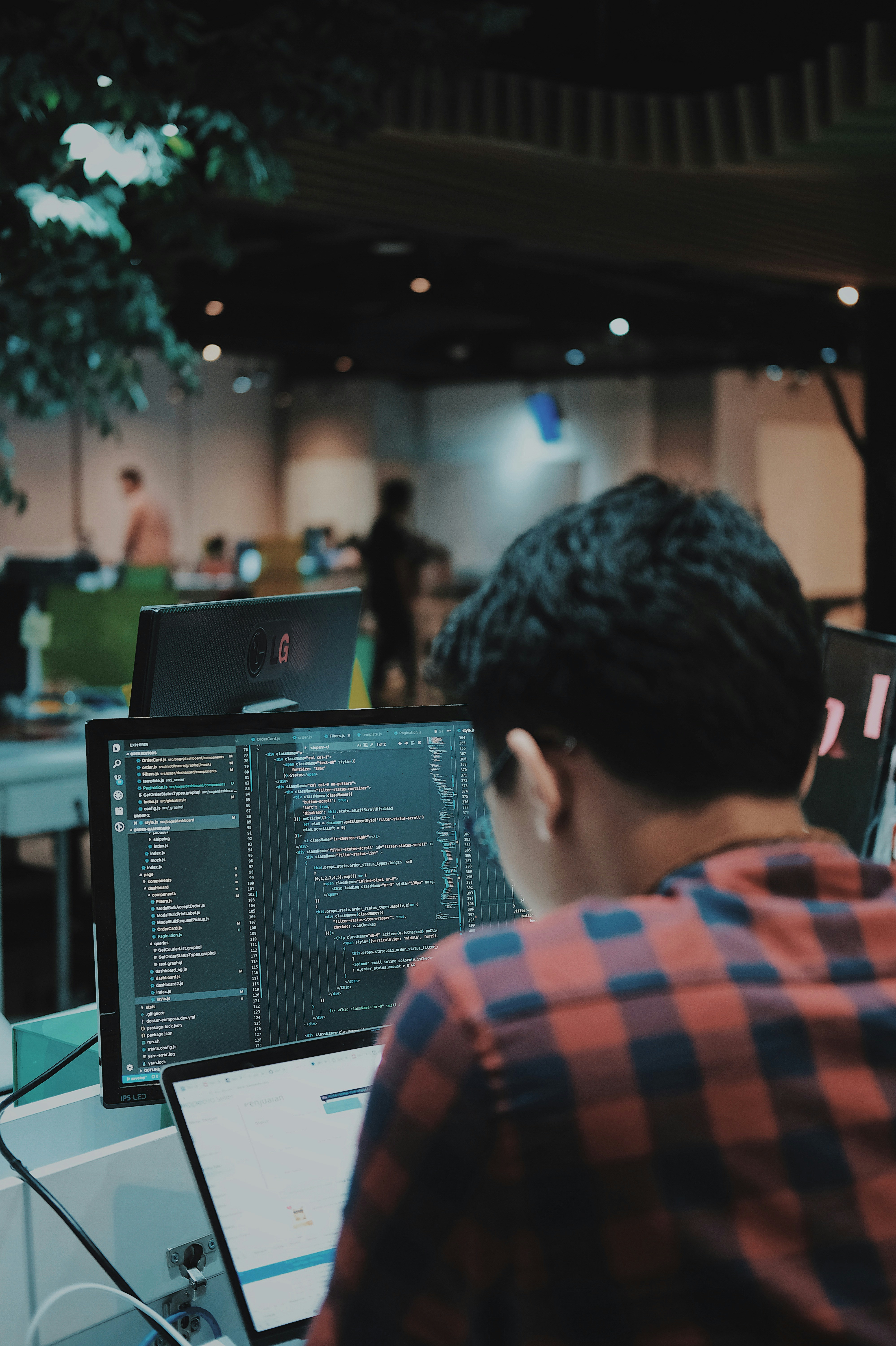 Developer reviewing code on dual monitors — schema, history, and source context inspected line by line
