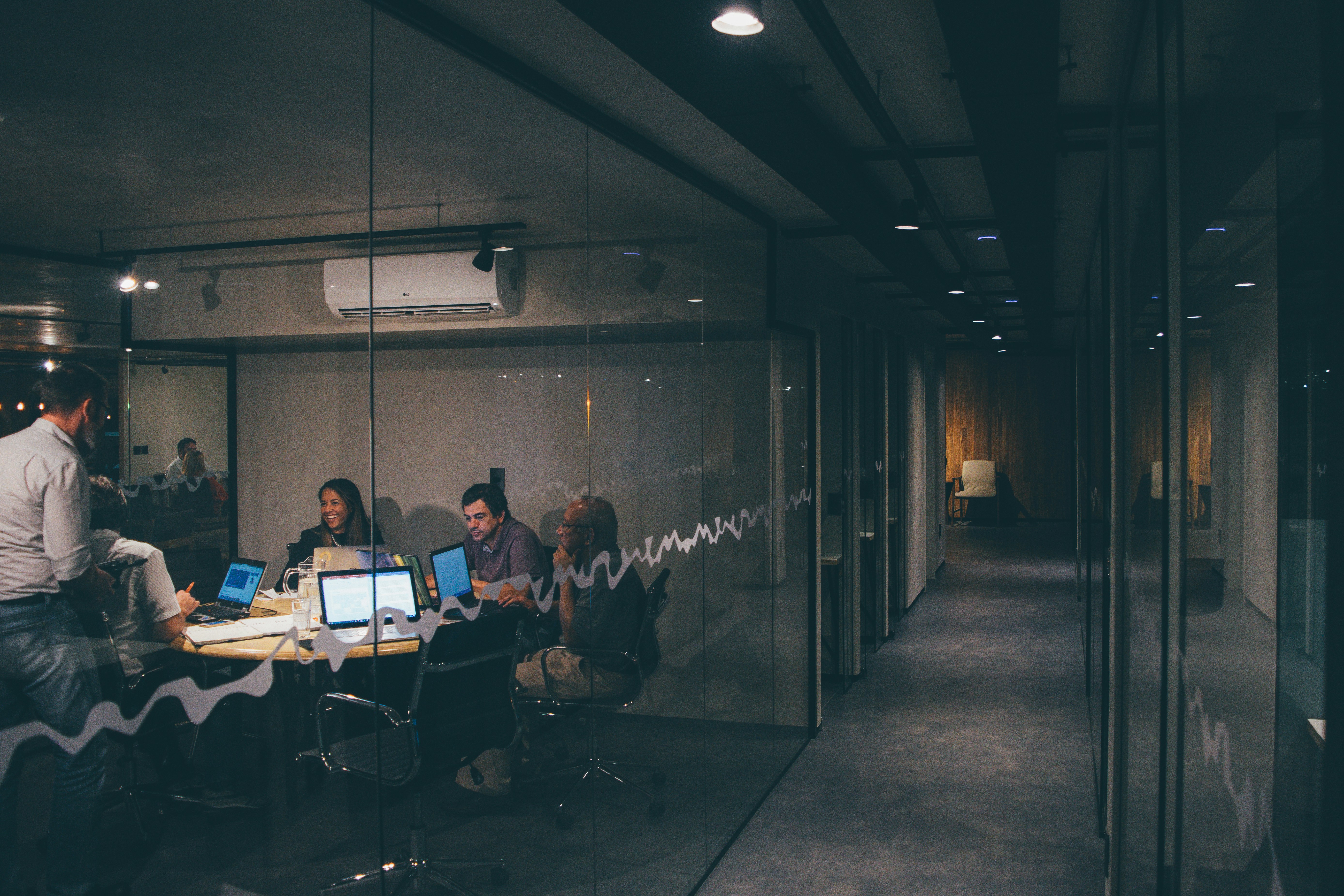A team collaborating with laptops in a modern glass-walled office