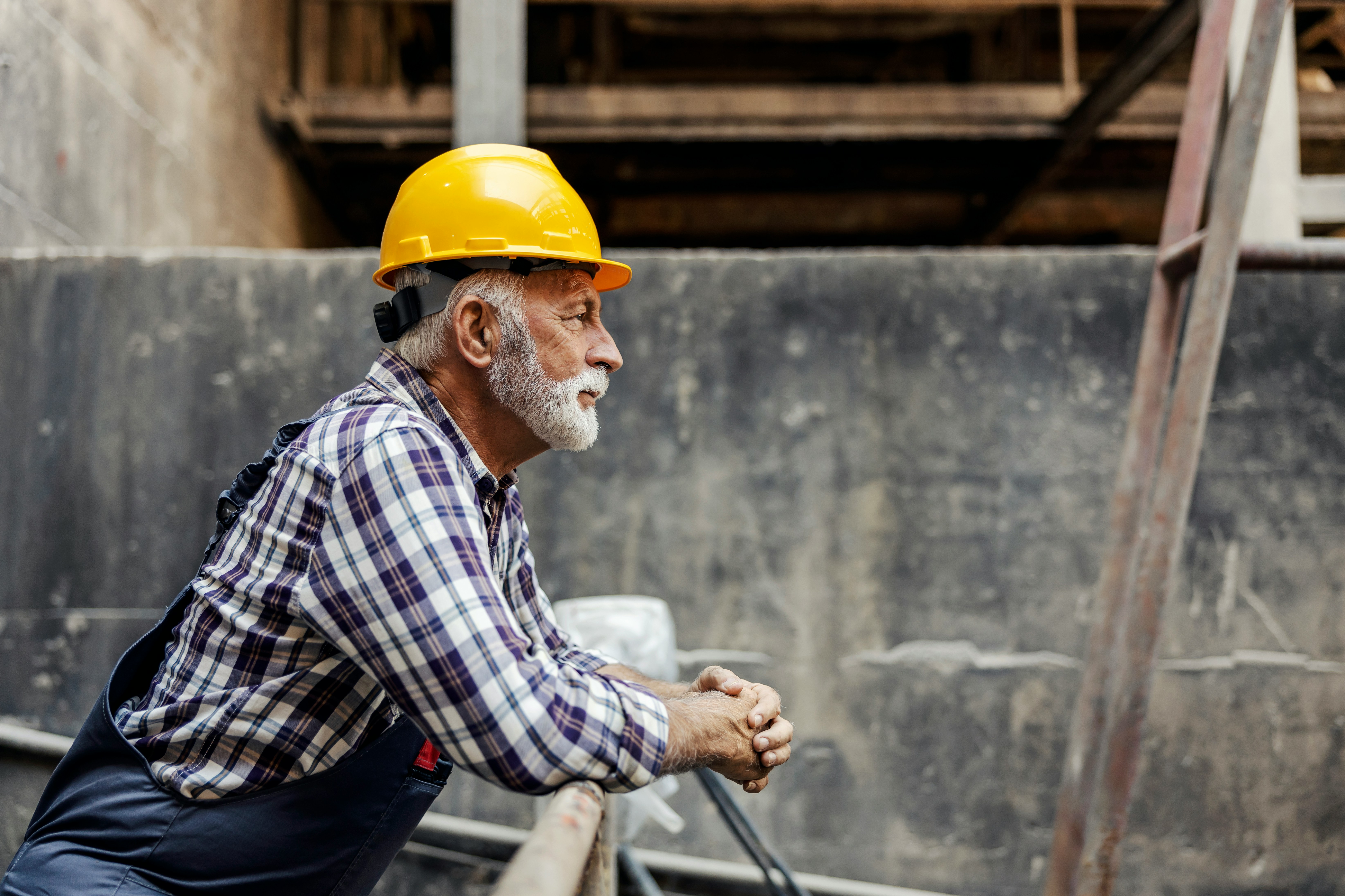 Senior warehouse worker in a hard hat, contemplative