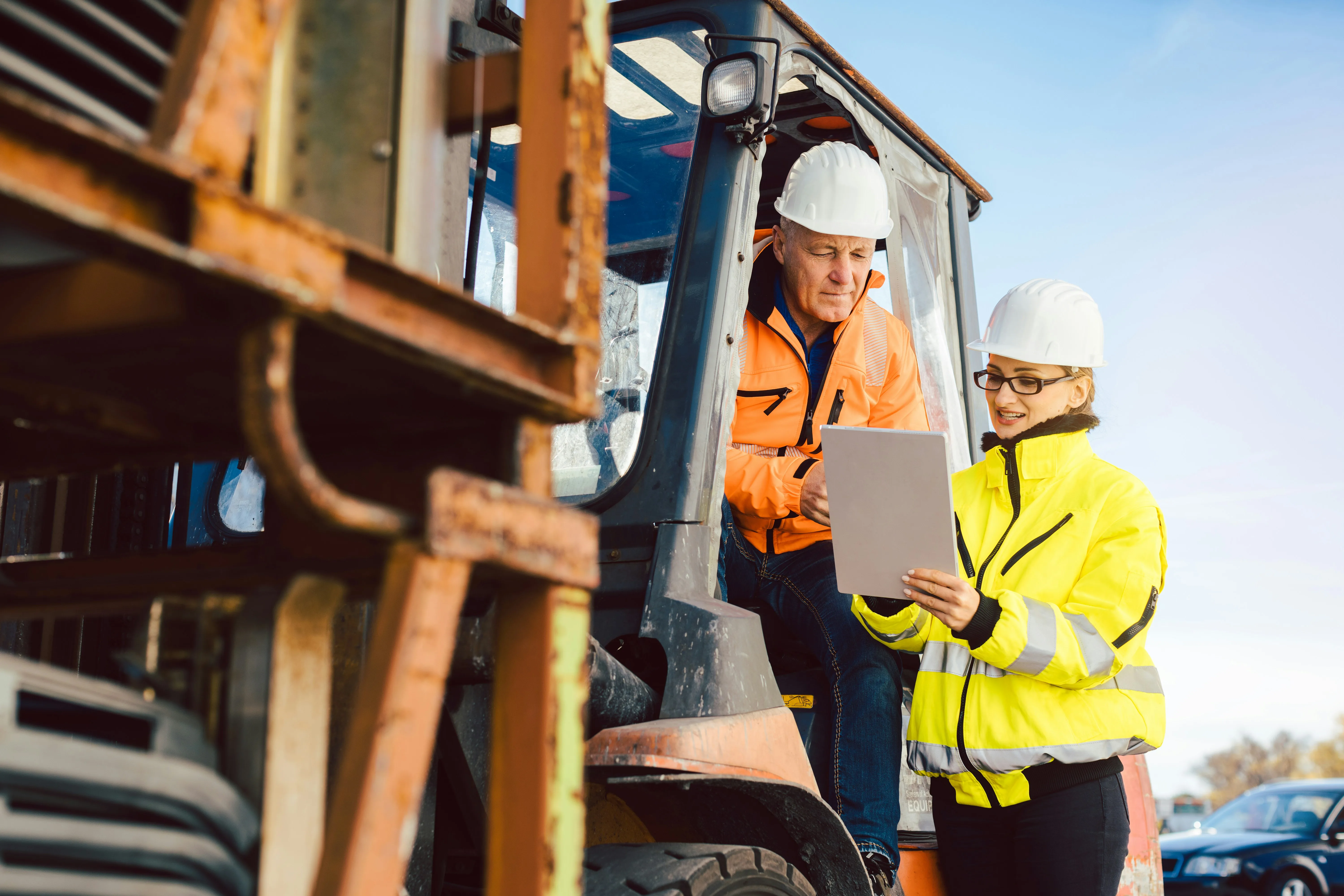 Warehouse workers using tablets near a forklift, connecting supply chain operations