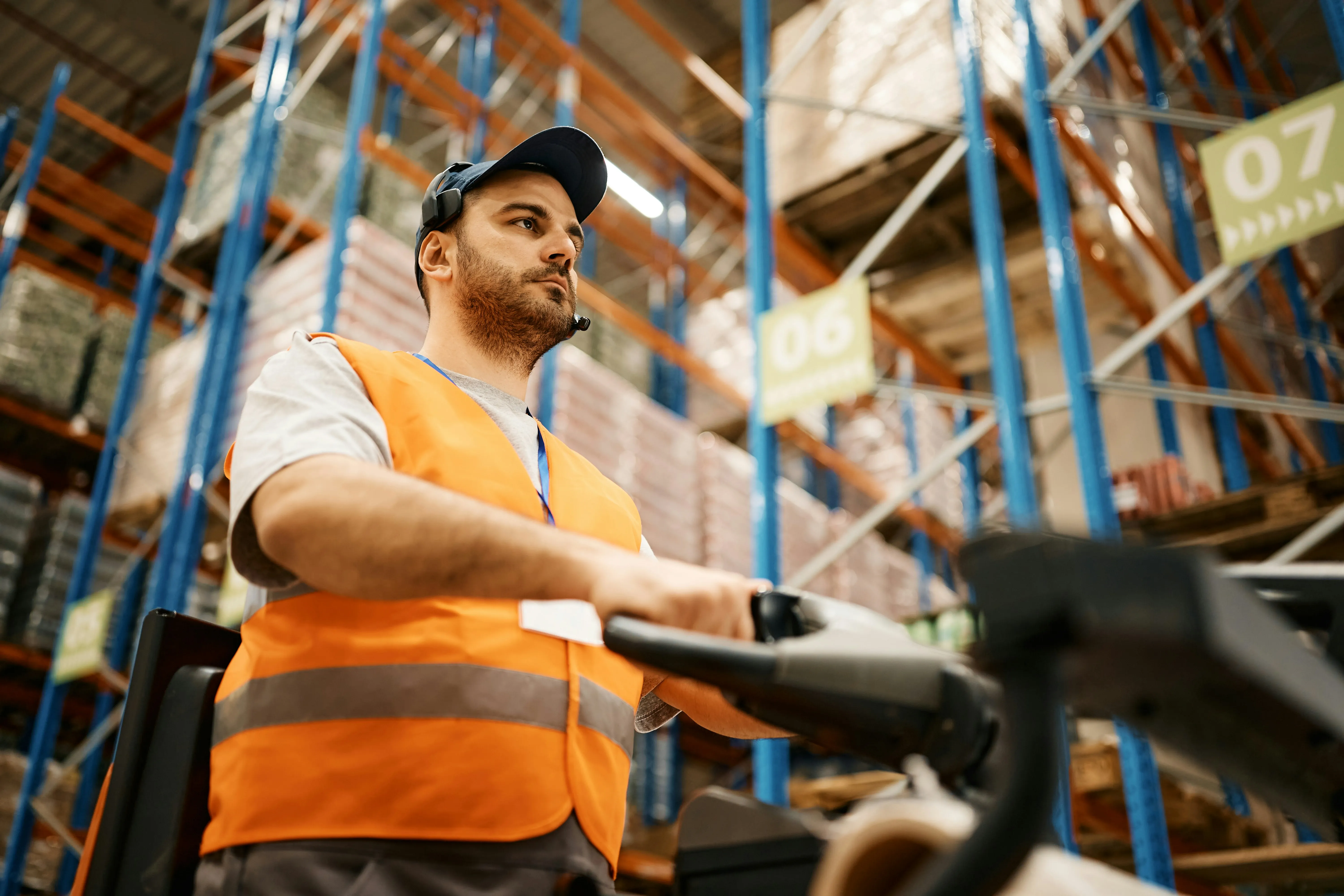 Focused forklift operator wearing a headset driving through a large warehouse — the operational systems your floor runs on